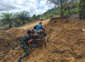 Personel Satgas TMMD Ke-128 Kodim 1204/Sanggau Bantu Warga Melintasi Jalan Rusak